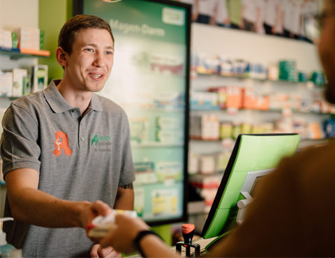 Beratungssituation in der Althoff Apotheke Neuwied, Mitarbeiter übergibt Medikament an Kunden am Verkaufstresen.