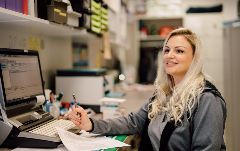 Mitarbeiterin der Althoff Apotheke bearbeitet Rezeptdaten am Computer im Backoffice-Bereich.