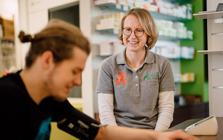 Blutdruckmessung in der Althoff Apotheke Neuwied, Beratungssituation am Verkaufstresen.